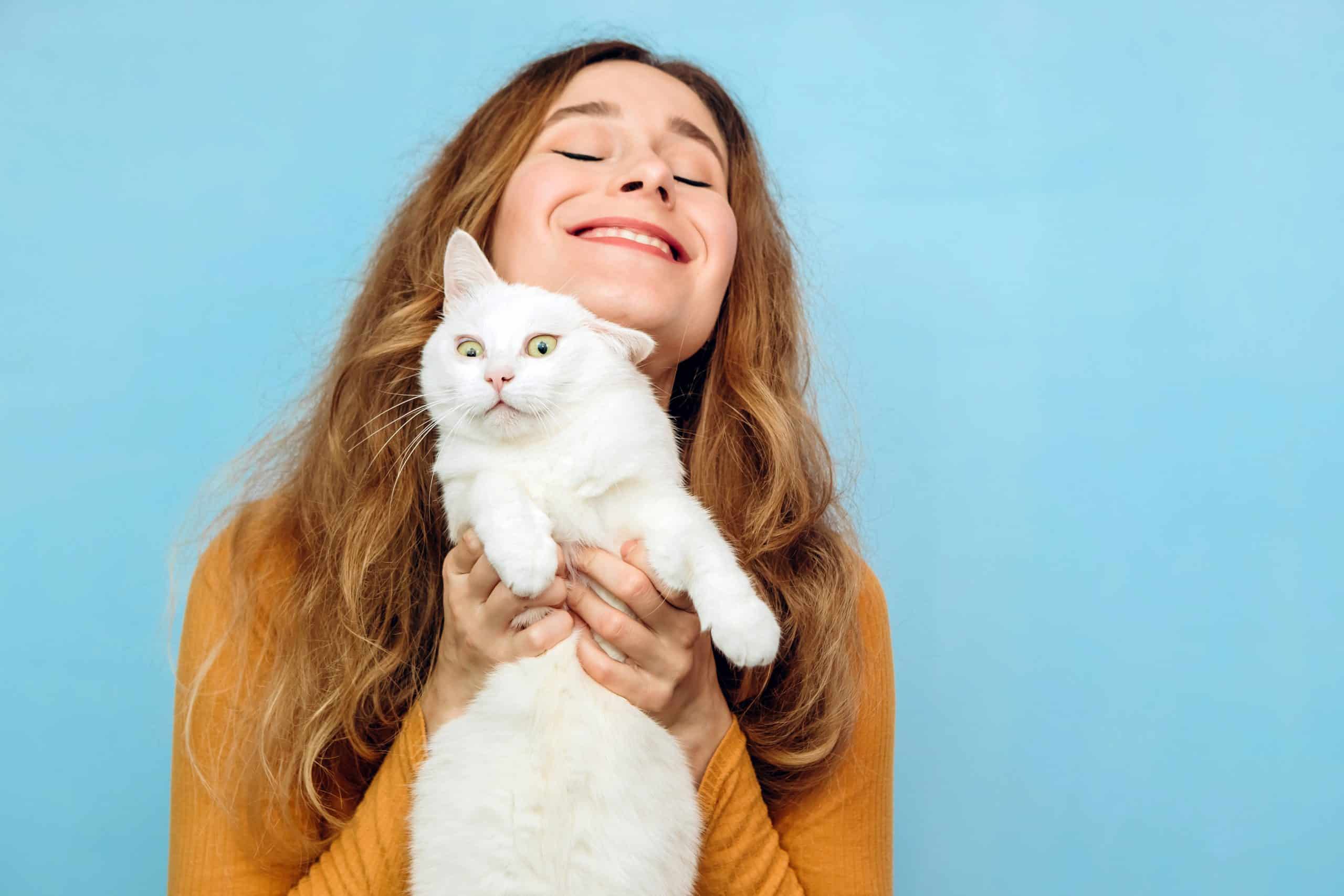 A young girl is holding a white cat in her arms
